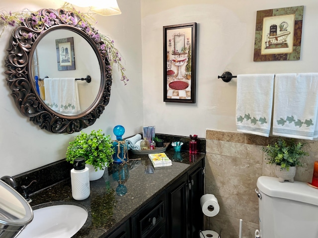 bathroom with tile walls, vanity, and toilet