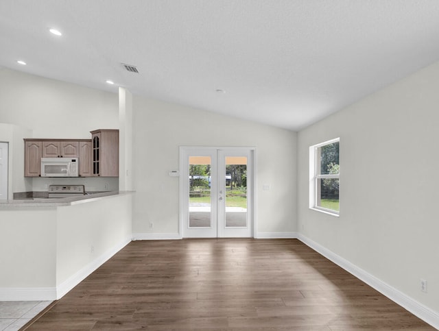 unfurnished living room with lofted ceiling, hardwood / wood-style floors, plenty of natural light, and french doors