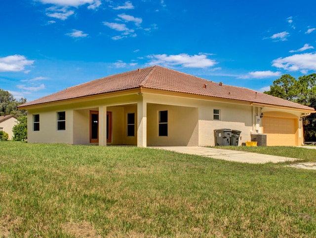 back of property with a garage, a yard, and central AC