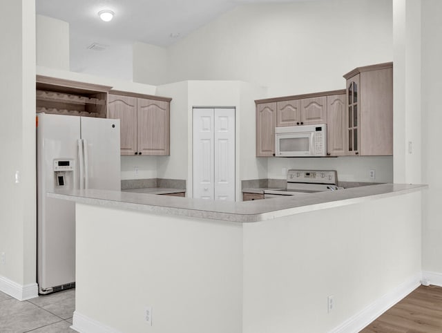 kitchen with white appliances, light brown cabinetry, and kitchen peninsula