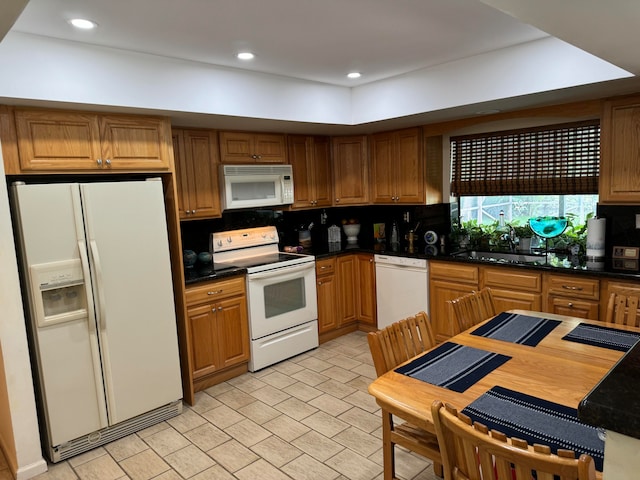 kitchen with decorative backsplash, white appliances, and sink