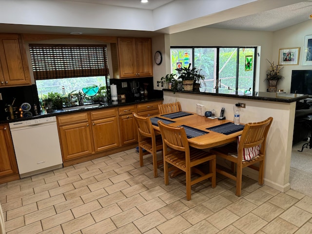 kitchen with decorative backsplash, dark stone counters, sink, dishwasher, and a textured ceiling