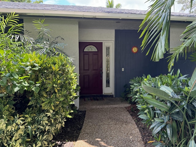 property entrance featuring roof with shingles and stucco siding