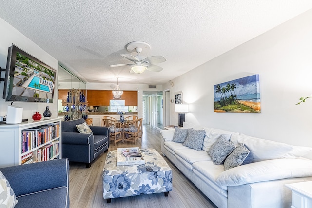 living room featuring light wood-type flooring, a textured ceiling, and ceiling fan