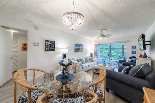 living room with ceiling fan with notable chandelier, a textured ceiling, and light hardwood / wood-style flooring