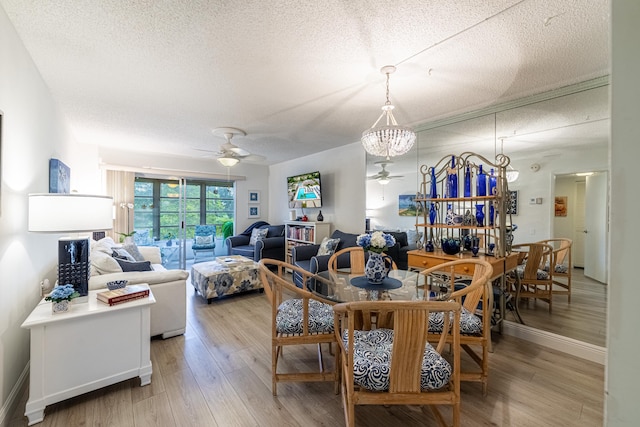 dining area with ceiling fan with notable chandelier, a textured ceiling, and hardwood / wood-style floors