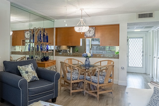 dining space featuring a textured ceiling, light hardwood / wood-style flooring, and a notable chandelier