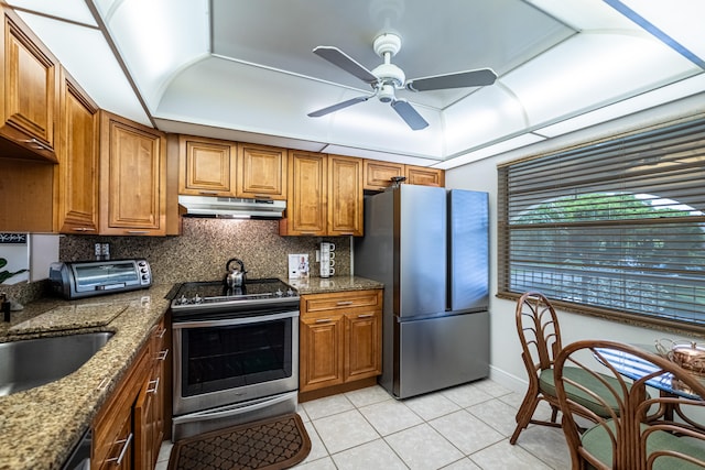 kitchen with stone counters, stainless steel appliances, light tile patterned flooring, ceiling fan, and decorative backsplash