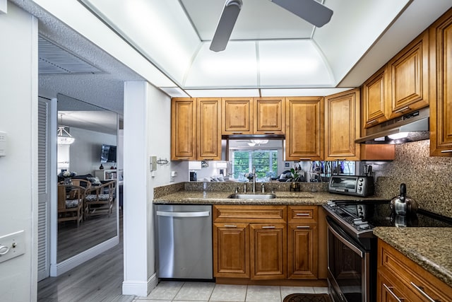 kitchen with dishwasher, electric range, sink, light wood-type flooring, and dark stone counters