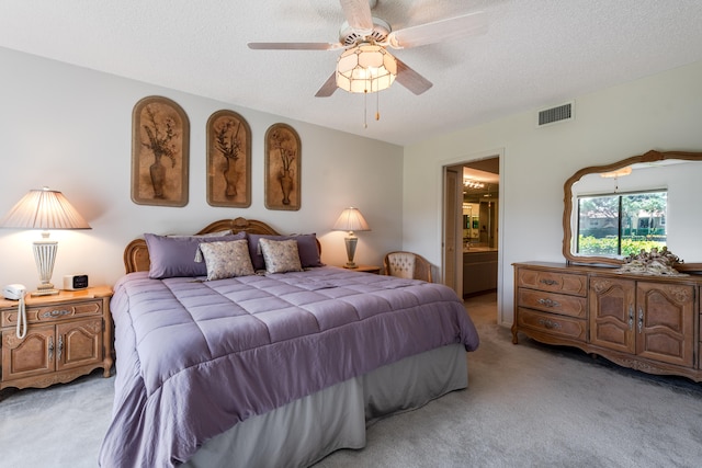 bedroom with a textured ceiling, ceiling fan, connected bathroom, and light colored carpet