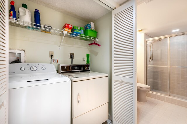 laundry room featuring light tile patterned floors, independent washer and dryer, and a textured ceiling