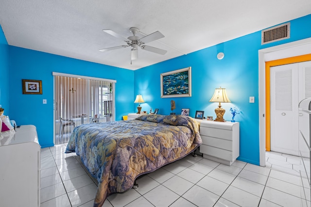 bedroom with ceiling fan, a closet, a textured ceiling, and light tile patterned floors