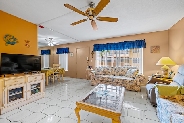 living room featuring ceiling fan, a fireplace, and light tile patterned floors