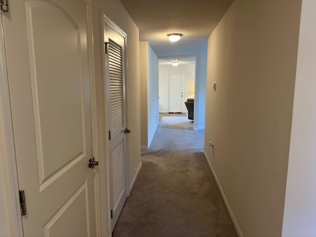 hall featuring a textured ceiling and light colored carpet