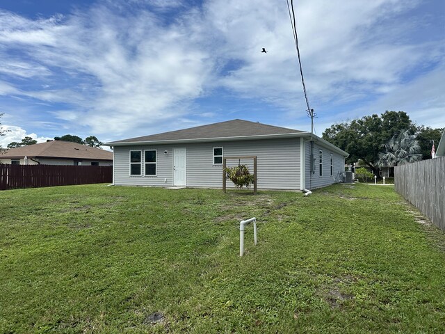 back of property featuring a yard, central AC, and fence