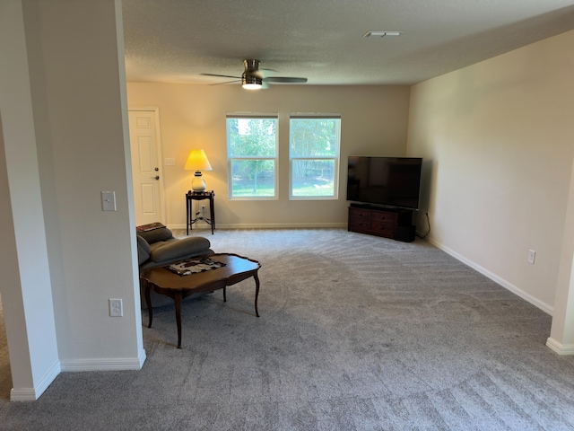 living room with ceiling fan, carpet flooring, and a textured ceiling