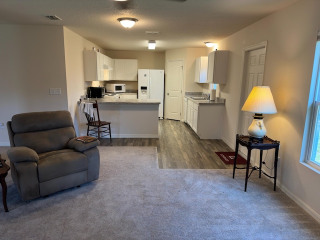 interior space with white cabinetry, kitchen peninsula, white appliances, and a breakfast bar area