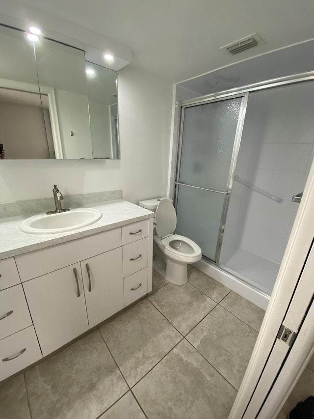 bathroom with tile patterned flooring, a shower with door, vanity, and toilet