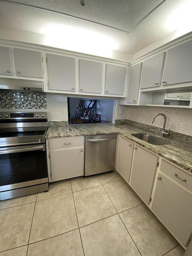 kitchen featuring appliances with stainless steel finishes, backsplash, sink, light tile patterned floors, and white cabinetry