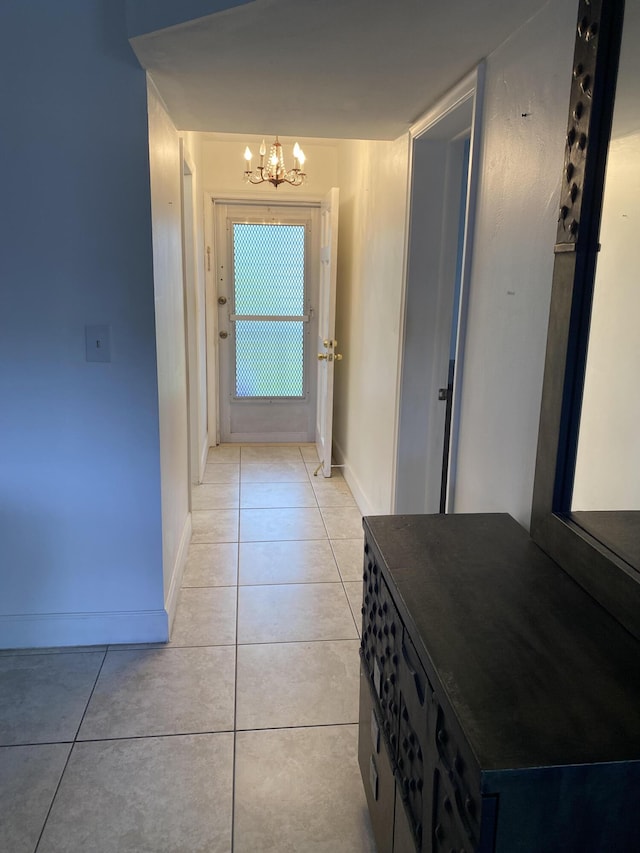 hallway with light tile patterned floors and a notable chandelier