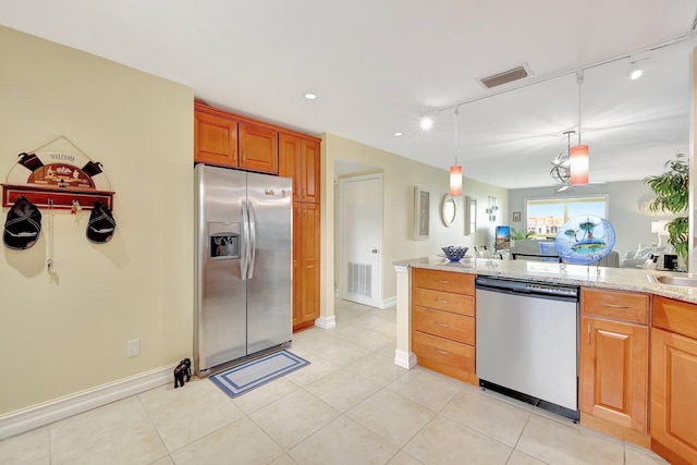 kitchen featuring rail lighting, decorative light fixtures, light tile patterned flooring, light stone counters, and stainless steel appliances