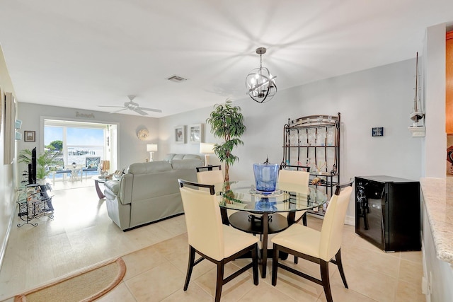 dining space with light tile patterned floors and ceiling fan with notable chandelier