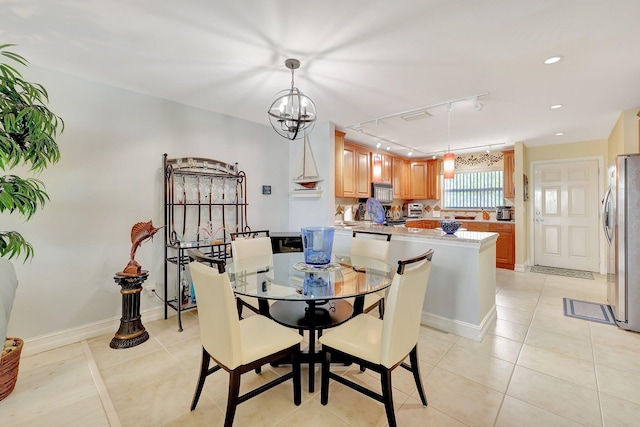 dining room with light tile patterned floors, track lighting, and an inviting chandelier