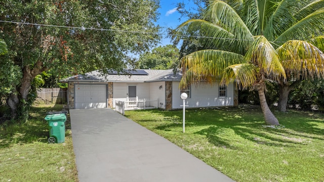 view of front of home with a garage, a front yard, and solar panels