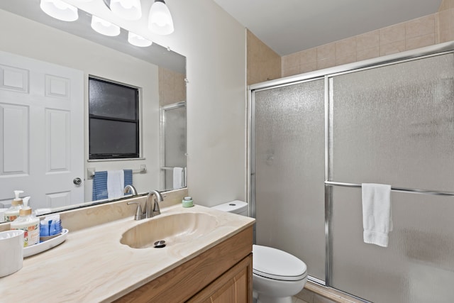 bathroom with vanity, toilet, and a shower with door