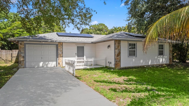 ranch-style house featuring a front lawn, a garage, and solar panels