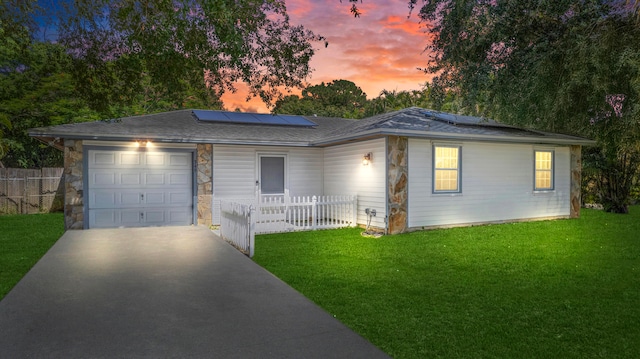 ranch-style home featuring solar panels, a garage, and a yard