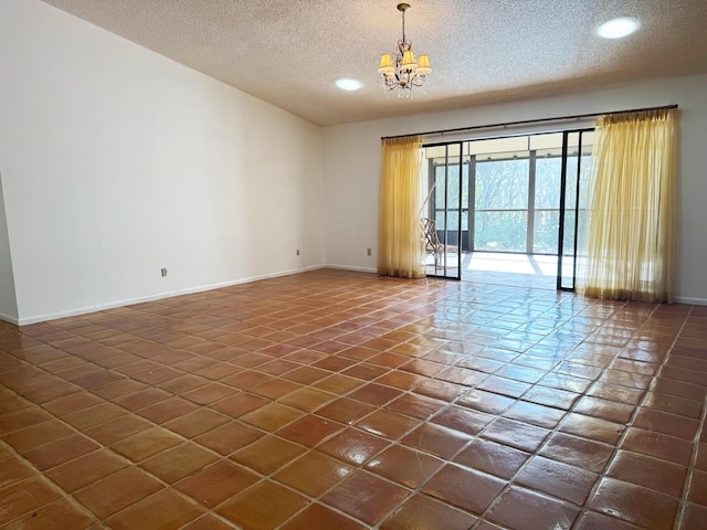 tiled empty room with a textured ceiling and a notable chandelier