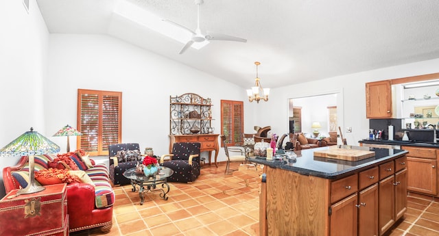 kitchen with light tile patterned flooring, lofted ceiling, ceiling fan with notable chandelier, sink, and a kitchen island