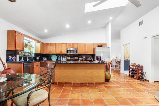 kitchen featuring a skylight, stainless steel appliances, high vaulted ceiling, decorative backsplash, and light tile patterned flooring