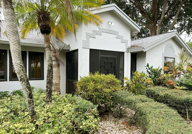 view of front facade featuring stucco siding and roof with shingles