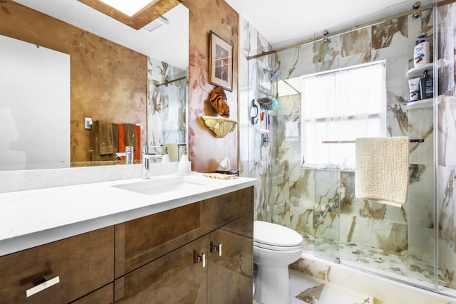 bathroom featuring vanity, a shower with shower door, and toilet