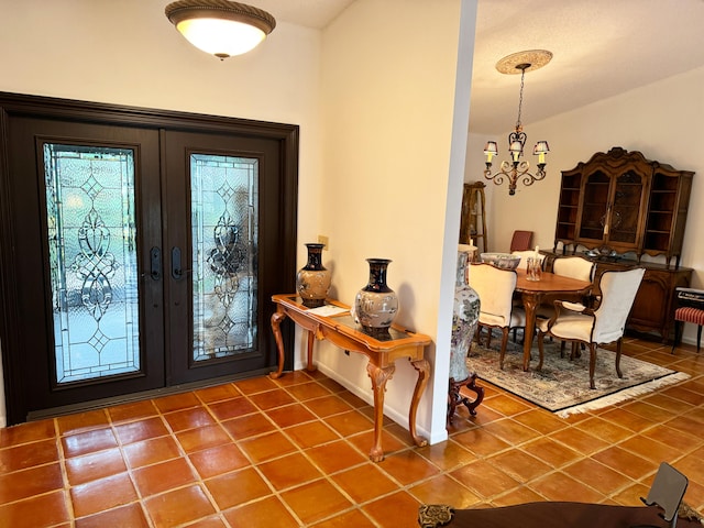 tiled foyer entrance with french doors and a chandelier