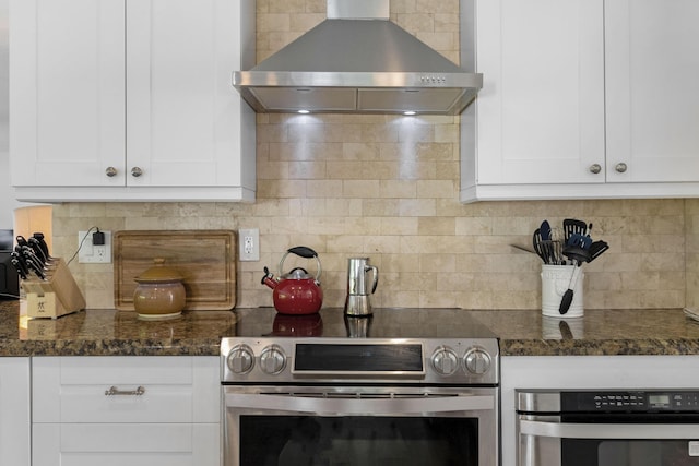 kitchen with stainless steel oven, stove, wall chimney exhaust hood, tasteful backsplash, and white cabinetry