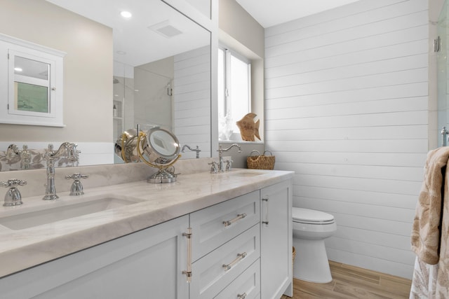 bathroom with hardwood / wood-style floors, vanity, toilet, and a shower with shower door