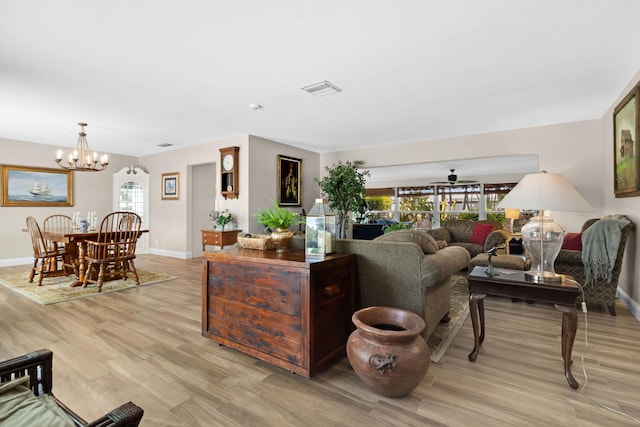 living room featuring ceiling fan with notable chandelier and light wood-type flooring