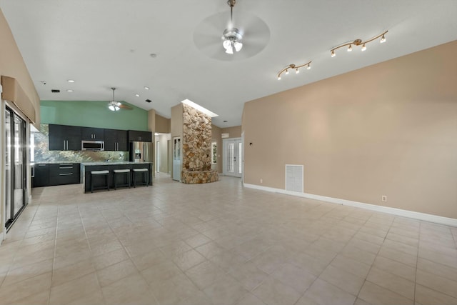 unfurnished living room with ceiling fan, light tile patterned flooring, and vaulted ceiling