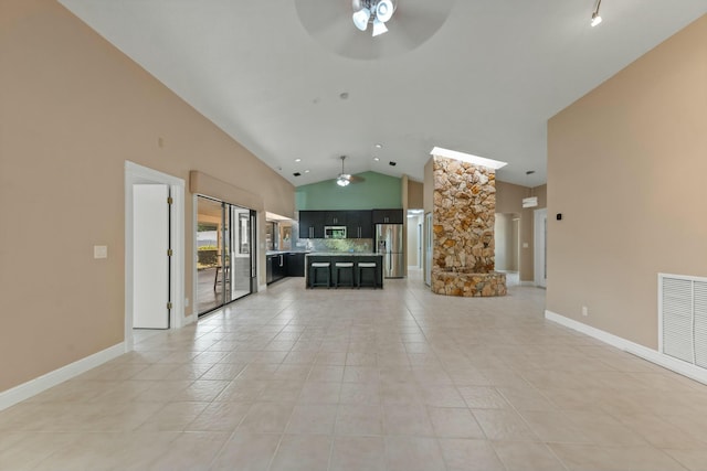 unfurnished living room featuring tile patterned flooring, vaulted ceiling, and ceiling fan