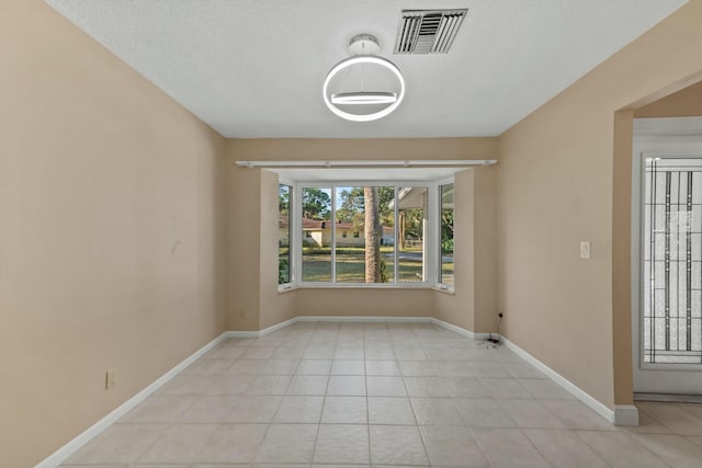 unfurnished room featuring light tile patterned flooring and a textured ceiling