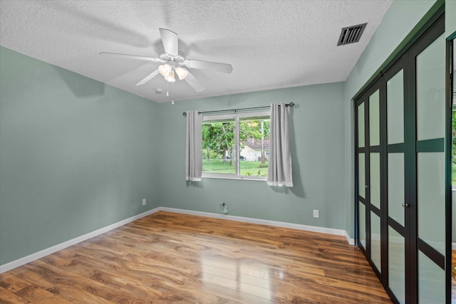 unfurnished room with hardwood / wood-style floors, a textured ceiling, and ceiling fan