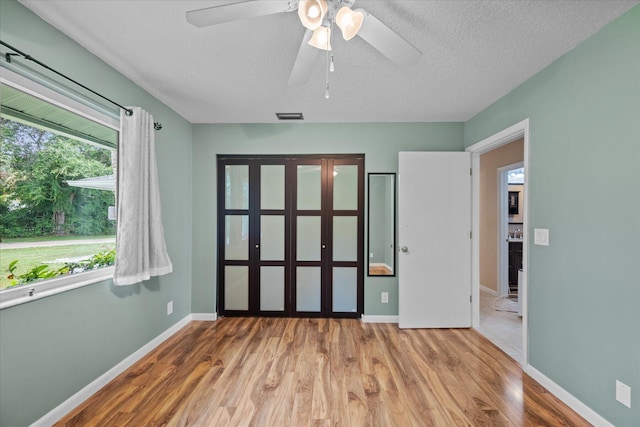 unfurnished bedroom with hardwood / wood-style flooring, ceiling fan, and a textured ceiling