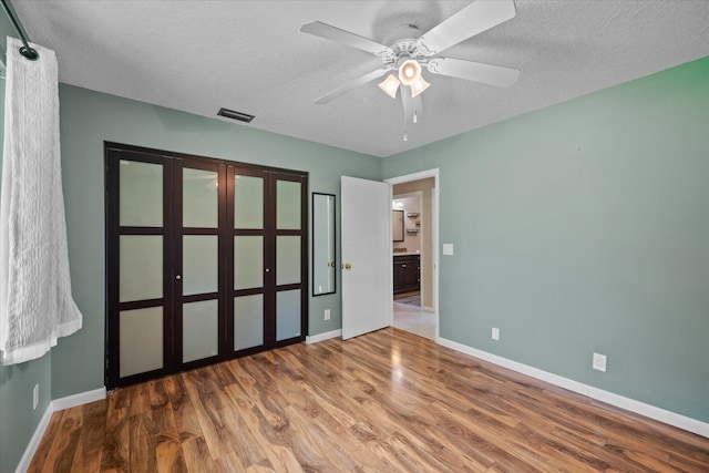 unfurnished bedroom with ceiling fan, wood-type flooring, and a textured ceiling