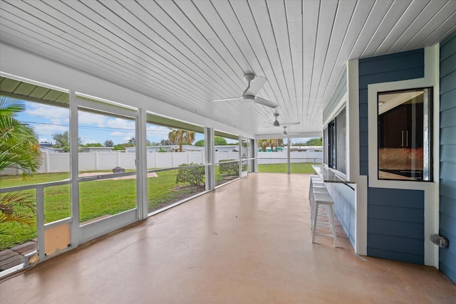 unfurnished sunroom with ceiling fan, a healthy amount of sunlight, and wood ceiling