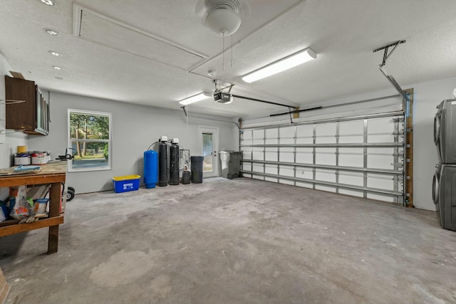 garage with a garage door opener and stacked washer / drying machine