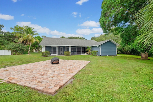 rear view of house with a sunroom, a yard, a patio, and an outdoor fire pit