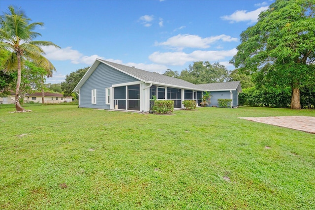 rear view of house with a lawn and a sunroom